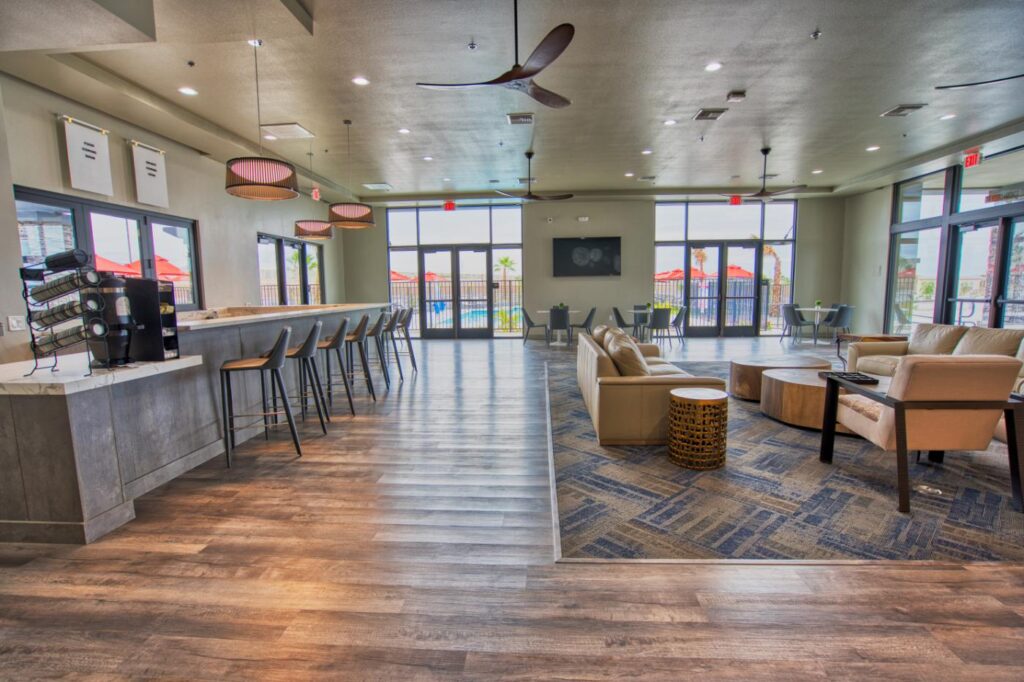 Spacious modern lounge with bar seating, armchairs, round tables, and large windows letting in natural light.